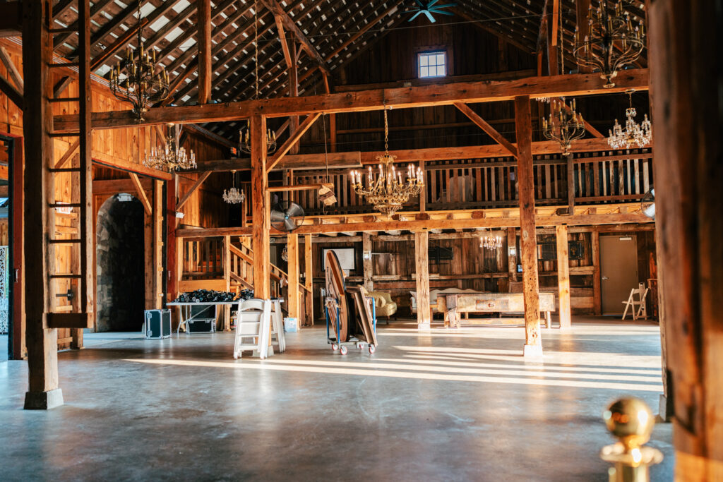 Interior of historic barn wedding venue featuring vintage chandeliers and soaring ceilings