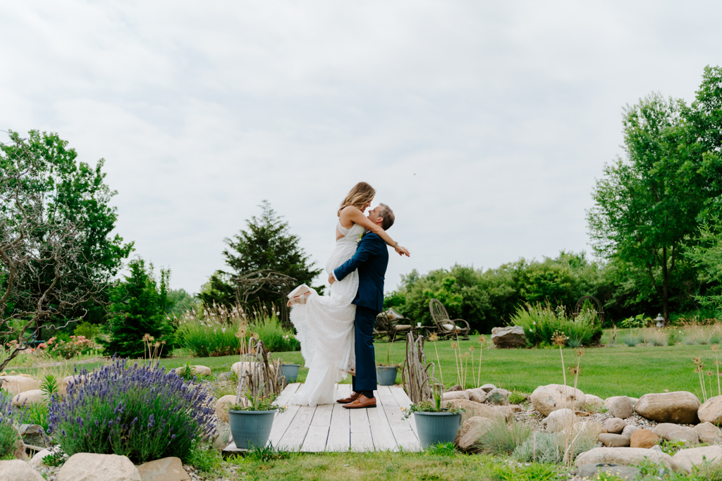 Newlyweds embrace on garden bridge during wedding at Inisfree Estate