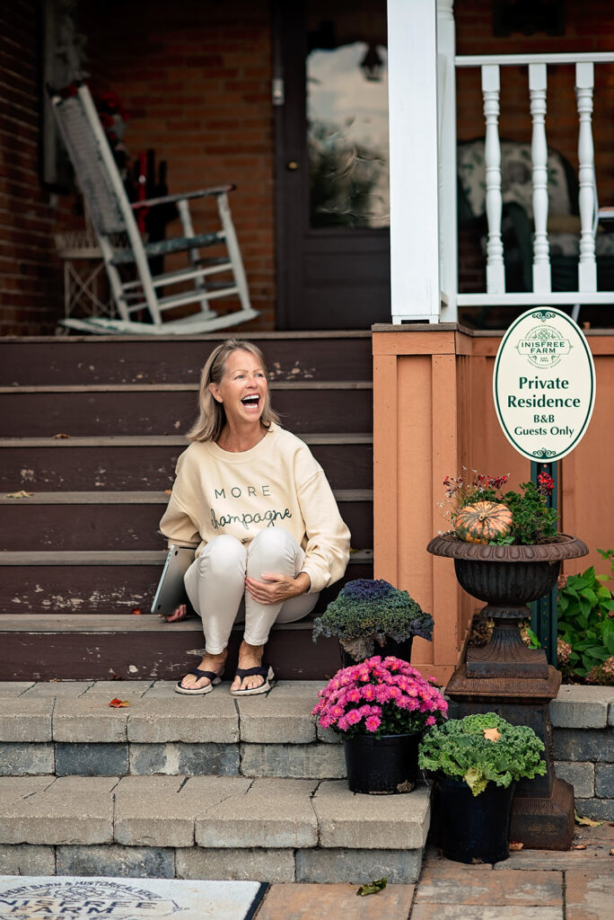 Inisfree Estate innkeeper, Peggy, sitting on the front steps at the inn