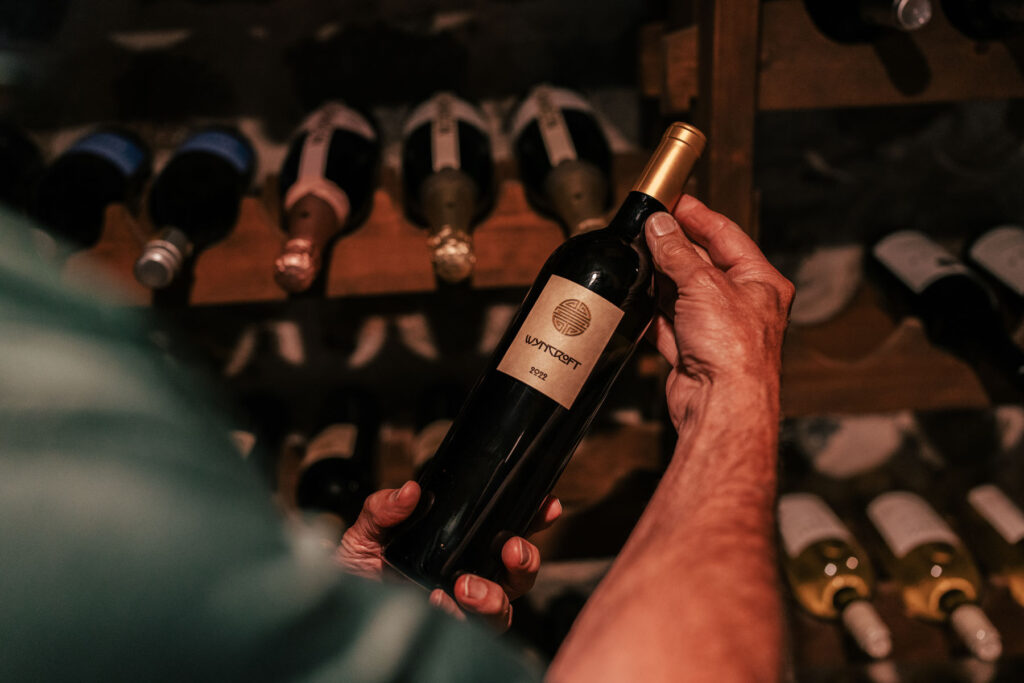 A bottle of Wyncroft Wine being held up in the Inisfree Estate wine cellar.